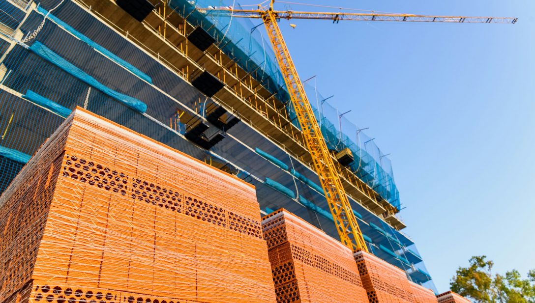 Yellow crane on a construction site to lift large weights of construction material.